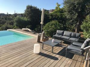 eine Terrasse mit einem Sofa und einem Tisch neben einem Pool in der Unterkunft Magnifique villa vue mer dans le golfe de St-Tropez in Roquebrune-sur-Argens