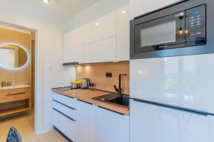 a kitchen with white cabinets and a microwave at Apartments Ivanka Cres in Cres