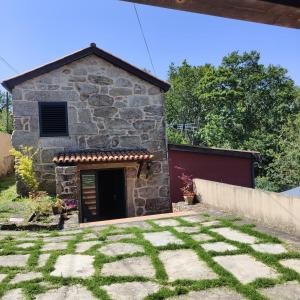 a stone building with a garage in a yard at Casa Ribadil in Crecíente