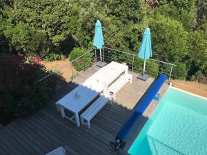ein Picknicktisch und zwei Sonnenschirme neben einem Pool in der Unterkunft Magnifique villa vue mer dans le golfe de St-Tropez in Roquebrune-sur-Argens