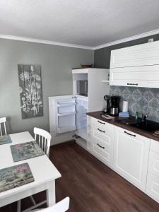 a kitchen with white cabinets and a table and a counter at Ferienhaus/Bungalow Lobbe - 60qm in Lobbe