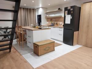 a kitchen with a black refrigerator and white cabinets at Sweet place in Saint-Denis
