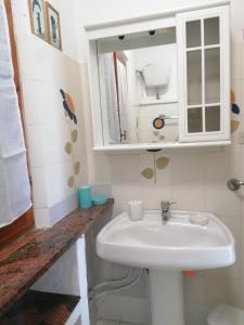 bagno con lavandino bianco e specchio di Dalla Manu 1/2 a Porto Istana