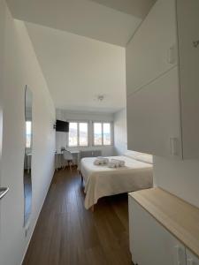 Settimo Cielo Apartment Aosta CIR 0199 في أَويستا: غرفة بيضاء مع سرير ومرآة