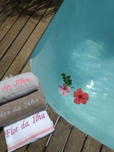 Una piscina de agua con dos toallas y flores. en Flor da Ilha Flats, en Isla de Boipeba