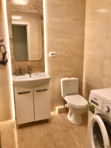 y baño con aseo, lavabo y lavadora. en 2-х кімн квартира в новобудові, en Ternopilʼ