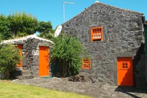 a stone house with orange doors and windows at Casas da Figueira in São Roque do Pico