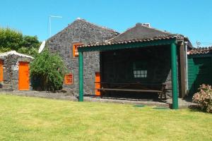 a stone house with a bench in the yard at Casas da Figueira in São Roque do Pico