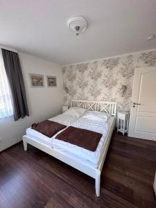 a bedroom with a white bed with floral wallpaper at Ferienwohnung Lobbe 2 - 100qm in Lobbe