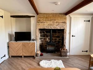 sala de estar con chimenea de piedra y TV en Swartha Cottages en Silsden