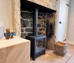 a stove in a living room with a stone wall at Swartha Cottages in Silsden