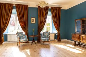 a blue room with two chairs and a table and windows at Skangaļu muiža in Skangaļi