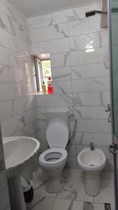 Baño blanco con aseo y lavamanos en Sweet Home, en Pogradec