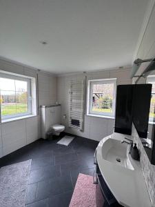 a bathroom with a sink and a toilet and two windows at Ferienwohnung Lobbe 1 - 120qm in Lobbe