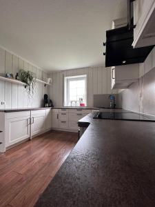 a large kitchen with white cabinets and a window at Ferienwohnung Lobbe 1 - 120qm in Lobbe