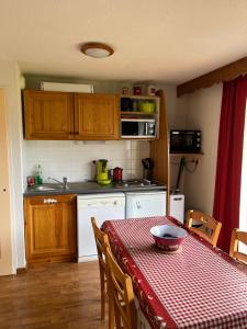 uma cozinha com uma mesa com uma toalha de mesa xadrez vermelha e branca em Appartement LA MARMOTTE DU DEVOLUY em Le Dévoluy