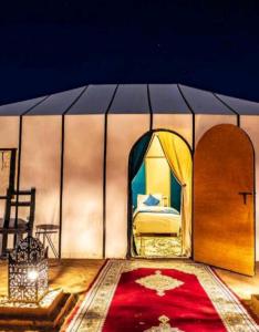 a bedroom with a bed in a tent with a red carpet at Luxury Local Camp in Merzouga