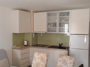 La cuisine est équipée de placards blancs et d'un réfrigérateur blanc. dans l'établissement Apartments Giana, à Labin