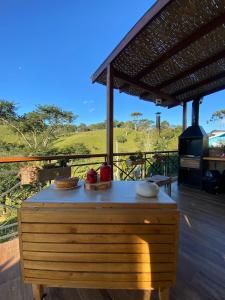 una mesa de madera en una terraza con parrilla en Linda vista para as montanhas a 5 min da cidade, en Santo Antônio do Pinhal