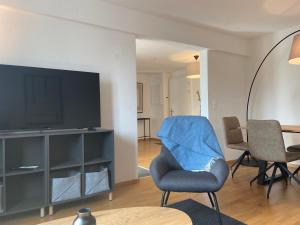 ein Wohnzimmer mit einem TV und einem blauen Stuhl in der Unterkunft 1 BDR Apartment in Zurich West in Zürich