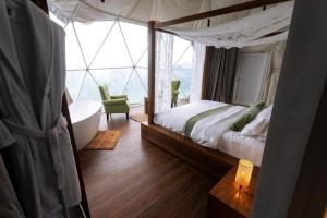 um quarto com uma cama de dossel, uma banheira e uma cadeira. em Serene Glamping سيرين em Salalah