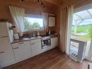 a kitchen with white cabinets and a large window at Sunset House in Sulęczyno