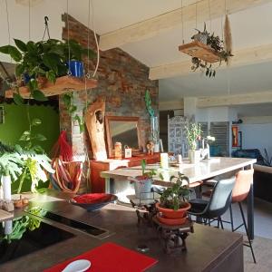 una sala de estar con mesa y muchas plantas en logement atypique avec jacuzzi et piscine, en Carnoules