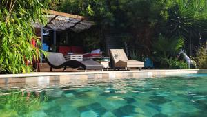 a pool of water with chairs and a table at logement de charme avec jacuzzi et piscine in Carnoules