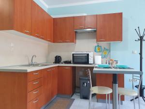 una piccola cucina con armadi in legno e forno a microonde di GM Apartments a Tolo