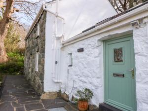 a white cottage with a green door on the side at Sweetholme in Caernarfon