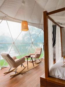 a bedroom with two chairs and a bed and a window at Serene Glamping سيرين in Salalah
