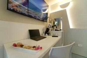 a desk with a laptop and a plate of food on it at Hotel Village Eden in Capo Vaticano