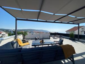 een patio met een bank en een tafel op een dak bij Apartment Agnes with 63 m2 Rooftop Terrace, Grill and Pool in Okrug Gornji