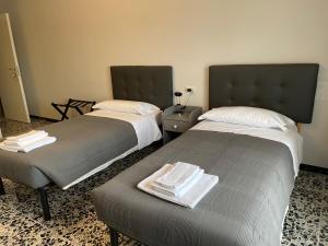 two beds in a hotel room with towels on them at La Locomotiva in Chiaravalle