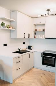 a white kitchen with white cabinets and a sink at Arra Apartments in Cluj-Napoca
