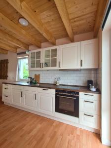 a kitchen with white cabinets and a wooden ceiling at Ferienhuette in Altfriesack