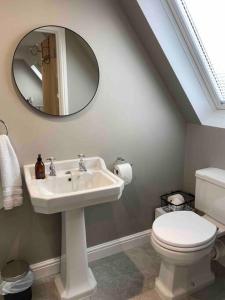 een badkamer met een wastafel, een toilet en een spiegel bij The Lodge in Birchington
