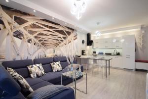 salon z niebieską kanapą i kuchnią w obiekcie Apartament Dobra Energia Kołobrzeg w Kołobrzegu