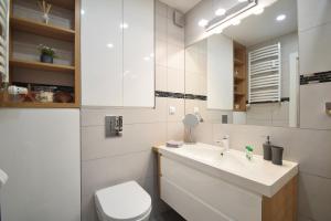 łazienka z umywalką, toaletą i lustrem w obiekcie Apartament Dobra Energia Kołobrzeg w Kołobrzegu