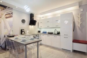 kuchnia z białymi szafkami i stołem z krzesłami w obiekcie Apartament Dobra Energia Kołobrzeg w Kołobrzegu +9 zdjęć