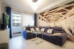 salon z niebieską kanapą i szklanym stołem w obiekcie Apartament Dobra Energia Kołobrzeg w Kołobrzegu