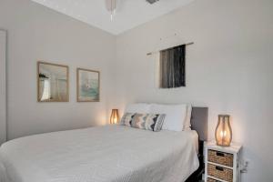 a white bedroom with a bed and two lamps at Classy 4BDRM Home W/Pool Mins To Beach and Shops! in Port Aransas