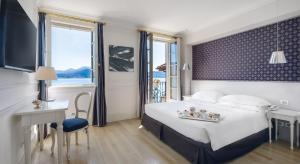 um quarto de hotel com uma cama, uma secretária e uma janela em Hotel Cannero em Cannero Riviera