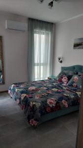 una camera da letto con un letto con un piumone floreale e una finestra di Anthic 7 Apartment 3 a Sozopol