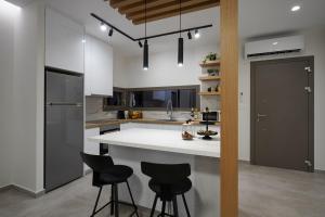 a kitchen with a white counter and black stools at Aegean Sunset Villas in Mastihari
