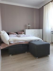 a bedroom with a large bed and a ottoman at Emi Apartament in Ogrodzieniec