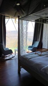 a bedroom with two chairs and a bed and a window at Serene Glamping سيرين in Salalah