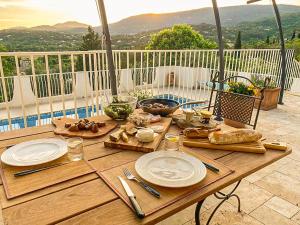 drewniany stół z talerzami jedzenia na patio w obiekcie Maison Fesch, vue panoramique, 120m2, Piscine, 3ch w mieście Fayence