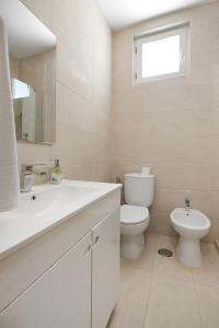 a white bathroom with a toilet and a sink at Villa Zara in Albufeira
