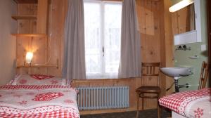 1 Schlafzimmer mit 2 Betten, einem Waschbecken und einem Fenster in der Unterkunft Staubbachbänkli in Wengen